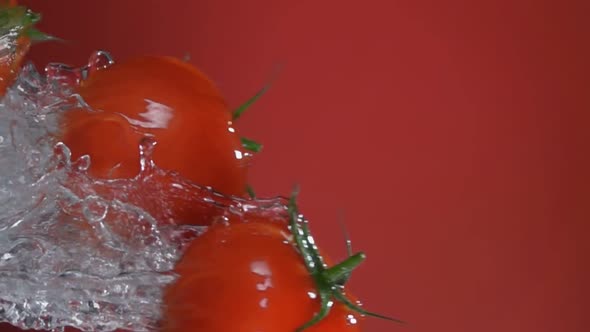 Wet Red Cherry Tomatoes are Flying Horizontally with the Splash of Water