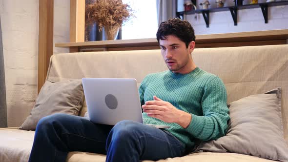 Upset and Sad Man Disappointed with Results on Laptop Sitting on Couch