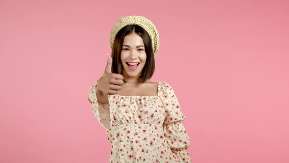 Cute Woman Showing Thumb Up Sign Over Pink Background. Positive Young Girl Smiles To Camera. Winner