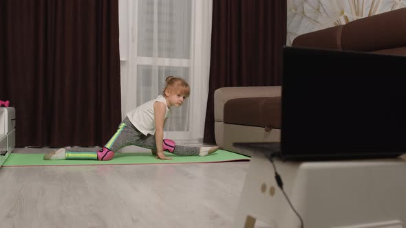 Children Girl Watching Online Distance Lessons with Trainer on Laptop Exercising Twine at Home