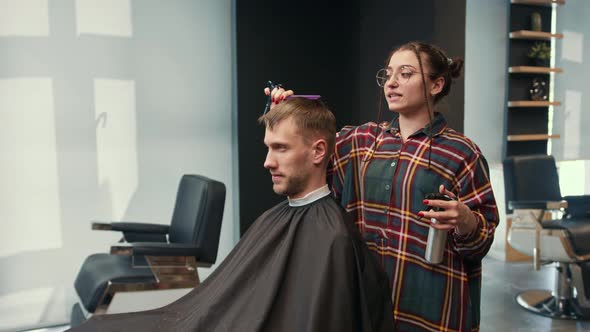 Barbershop: a woman barber cuts a client's man's hair