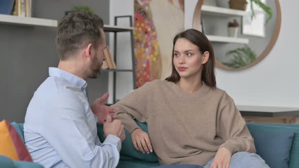 Man Talking to Woman While Sitting on Sofa