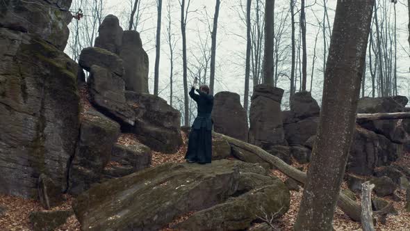 Man in Traditional Japanese Clothes, with a Sword, a Katana, Trains Martial Arts in the Forest