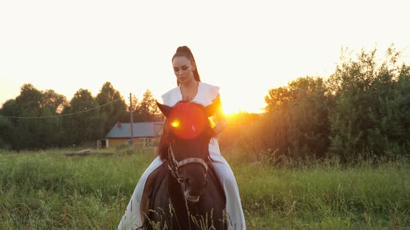 Professional Model Rides Large Stallion Along Meadow