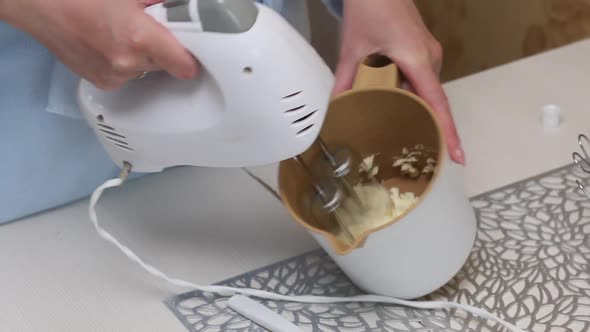 A Woman Whips Butter Into A Cream Using A Mixer. Baking Tray With Meringue For Cake