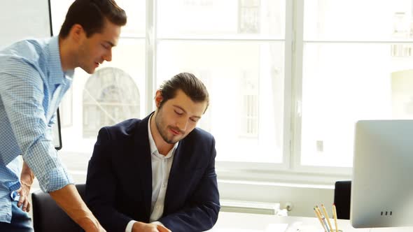 Business colleagues discussing on blueprint