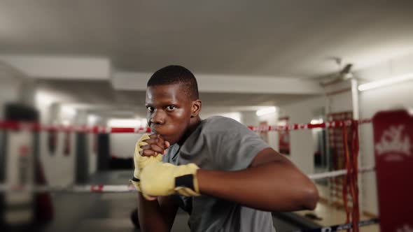 Young Confident African Male Boxer Wearing Boxing Bandage on Hands Punching at Camera During Workout
