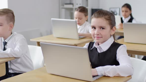 Caucasian Schoolgirl with Laptop Smiling for Camera in Class