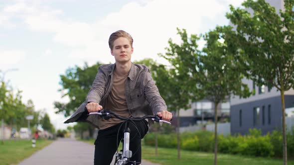 Young Man Riding Bicycle on City Street