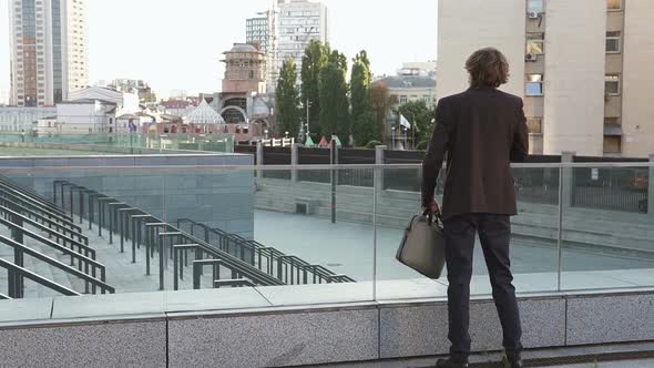 A successful and in a good mood businessman listens to music near the office.