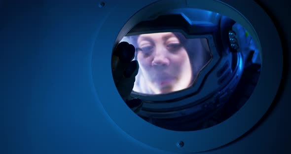 Female Astronaut Looking Out of Spaceship Porthole