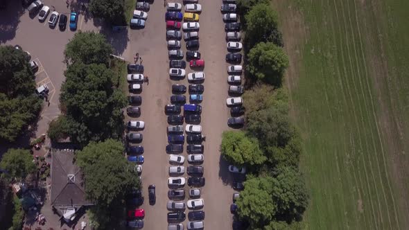 Drone aerial top down over busy Trent Park car park in North London panning up to reveal entrance/ex