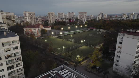 Aerial View of Football Soccer Fields in City Park Against Urban Landscape in the Evening