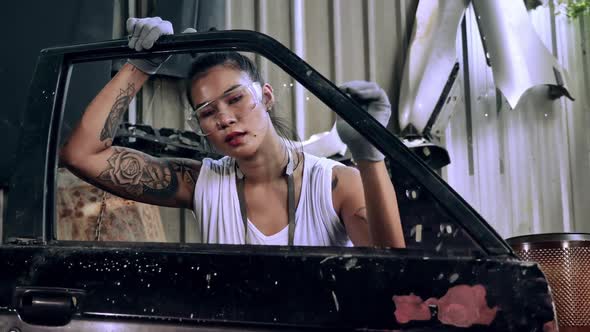 Attractive young woman mechanical worker repairing a vintage car in old garage.