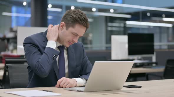 Businessman Having Neck Pain While Using Laptop in Office