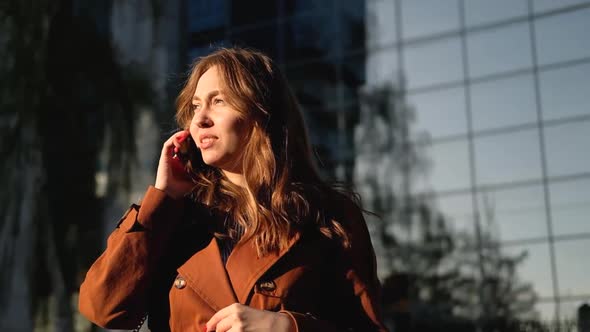 Young woman having phone call outdoors. Girl talking on the phone on the street