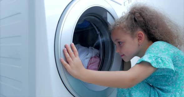 Close Up Cute Child Looks Inside the Washing Machine. Cylinder Spinning Machine. Concept Laundry