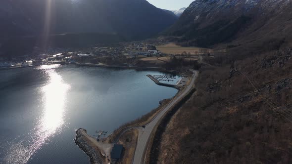 Morning sunshine over Eidfjord city centre, marina and roads - calm idyllic fly in scene - Norway