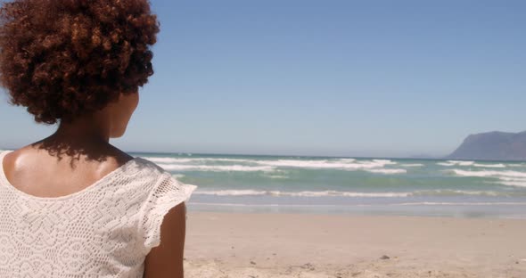Rear view of young African american woman relaxing on beach in the sunshine 4k