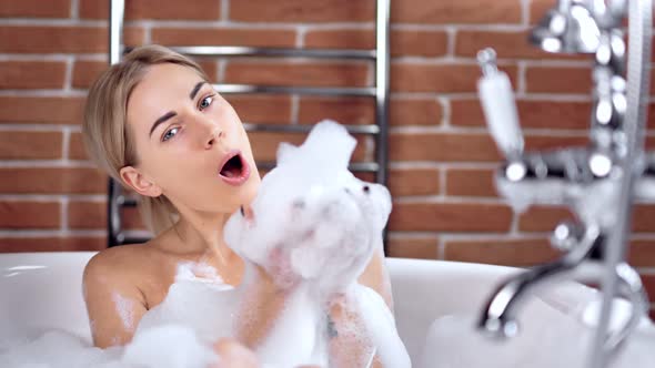 Medium Closeup Portrait of Beautiful Seductive Smiling Young Woman Taking Bath with Foam