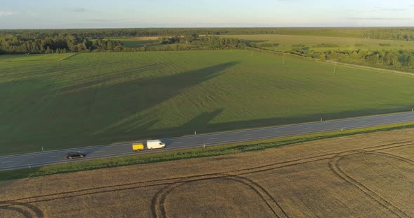 Aerial View of Cars and Cargo Truck Driving on Highway in Countryside at Sunset
