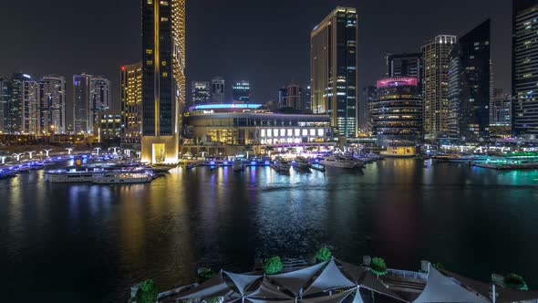 Aerial Vew of Dubai Marina with Shoping Mall Restaurants Towers and Yachts Night Timelapse United