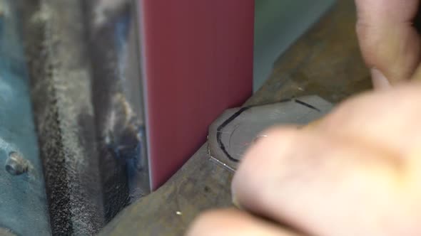 Sanding belt used to grind metal part for creating furniture joint, Close up handheld shot