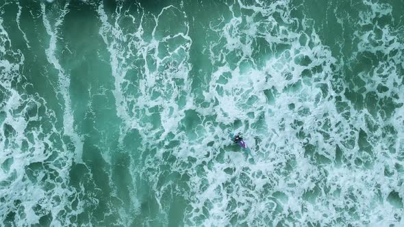 Surfer catching a wave from above. Birds-eye-view shot.