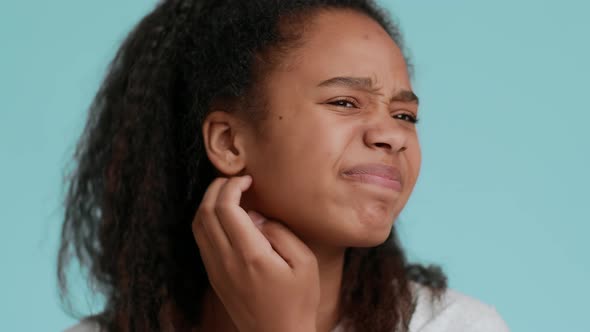 African Teen Girl Scratching Itching Neck Posing Over Blue Background