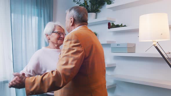 Happy Elderly Couple Dancing at Home in Formal Wear