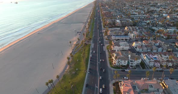 A drone flies above Pacific Coast Highway traffic and beautiful luxury homes overlooking the beach.