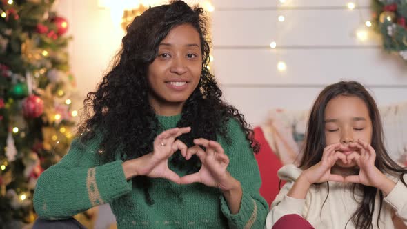 Daughter and Black Mother Show Hearts with Fingers Smiling