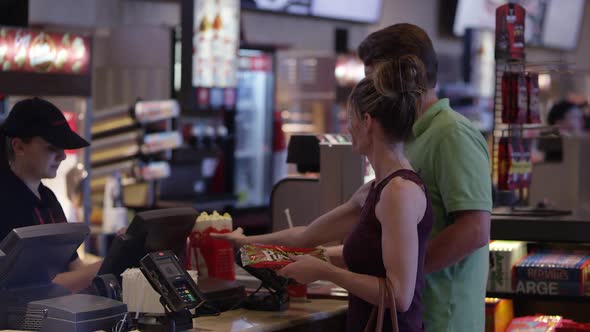 Man and woman paying for popcorn and drink at movie theater