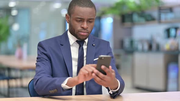 Serious African Businessman Using Smartphone in Office