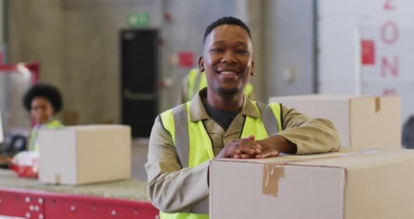 Portrait of african american male worker wearing safety suit and smiling in warehouse