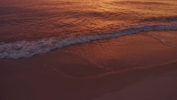 Sea surf against the background of an orange sunset