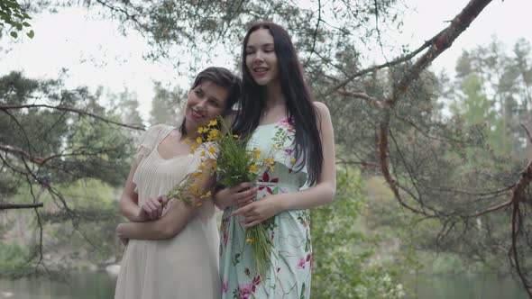 Portrait Two Pretty Young Women in Summer Dresses Standing on Rocky Ground with Wild Flowers