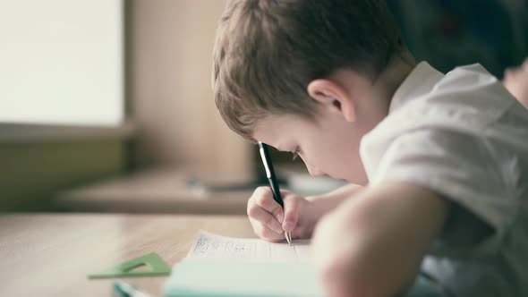 Children Do Their Homework, One Sits at the Table with Notebooks