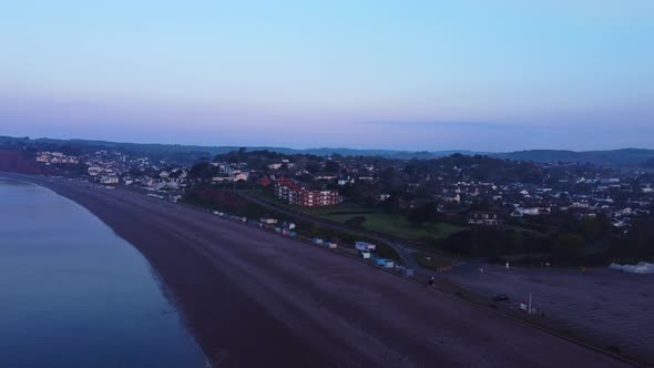 Aerial drone fly over English coast beach town in Devon at sunrise twilight, beautiful landscape