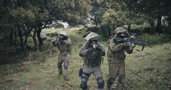 Squad of fully armed commando soldiers during combat in a forest scenery