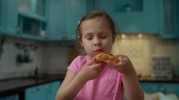 Preschool girl in pink t-shirt eating homemade pizza at home