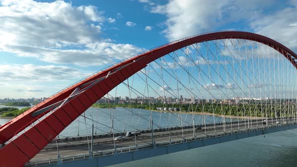 Car traffic on the arch road bridge across the river in the city in summer. Aerial view