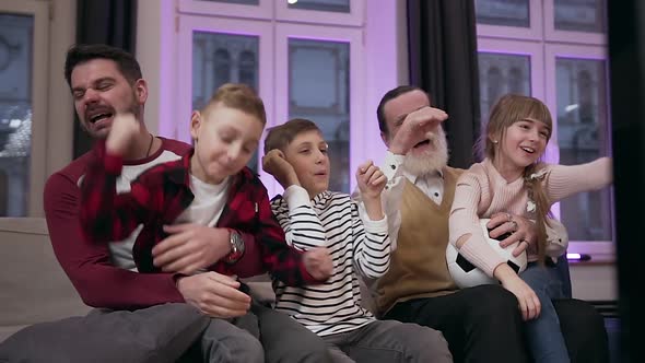 Dad and Granddad with Cheerful Grandchildren Having Fun Together During Revisioning Sport Game