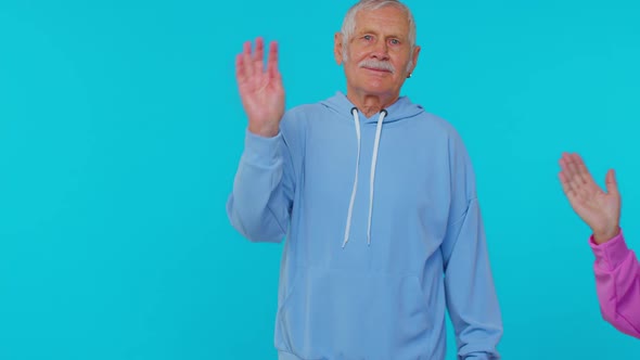 Senior Grandmother Grandfather Walking Opposite Camera Waving Hands Gesturing Hello or Goodbye