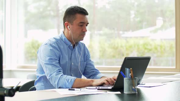 Man in Earphones with Laptop Working at Home