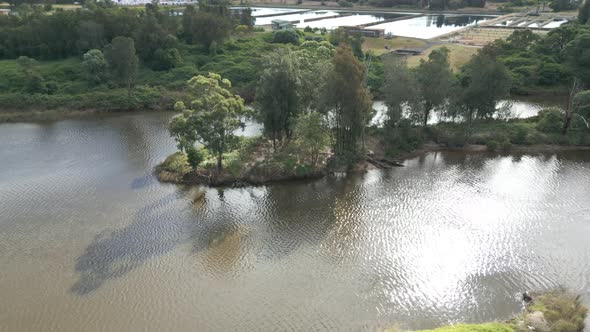 Beautiful aerial scenery of drone flying over a river and island in the middle on a sunny day