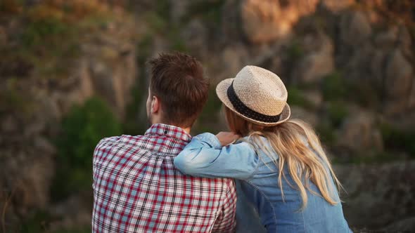 Young Male in Plaid Shirt Sitting with Girlfriend in Jeans Shirt and Hat