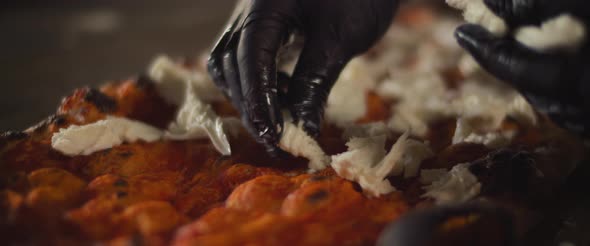 Close up of a chef spreading burrata cheese over a traditional al taglio pizza.