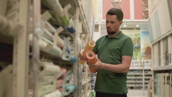 Master is Comparing Two Kind of Wallpaper in a Shop Shopping for Repairs