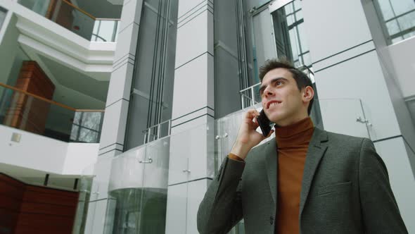 Businessman Walking in Office Center and Speaking on Phone